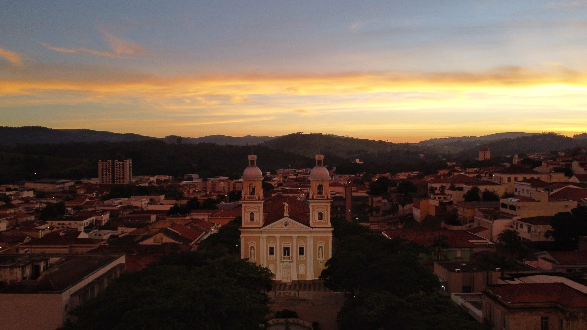 Vista aérea do centro de Amparo ao entardecer, com a Catedral de Nossa Senhora do Amparo ao centro