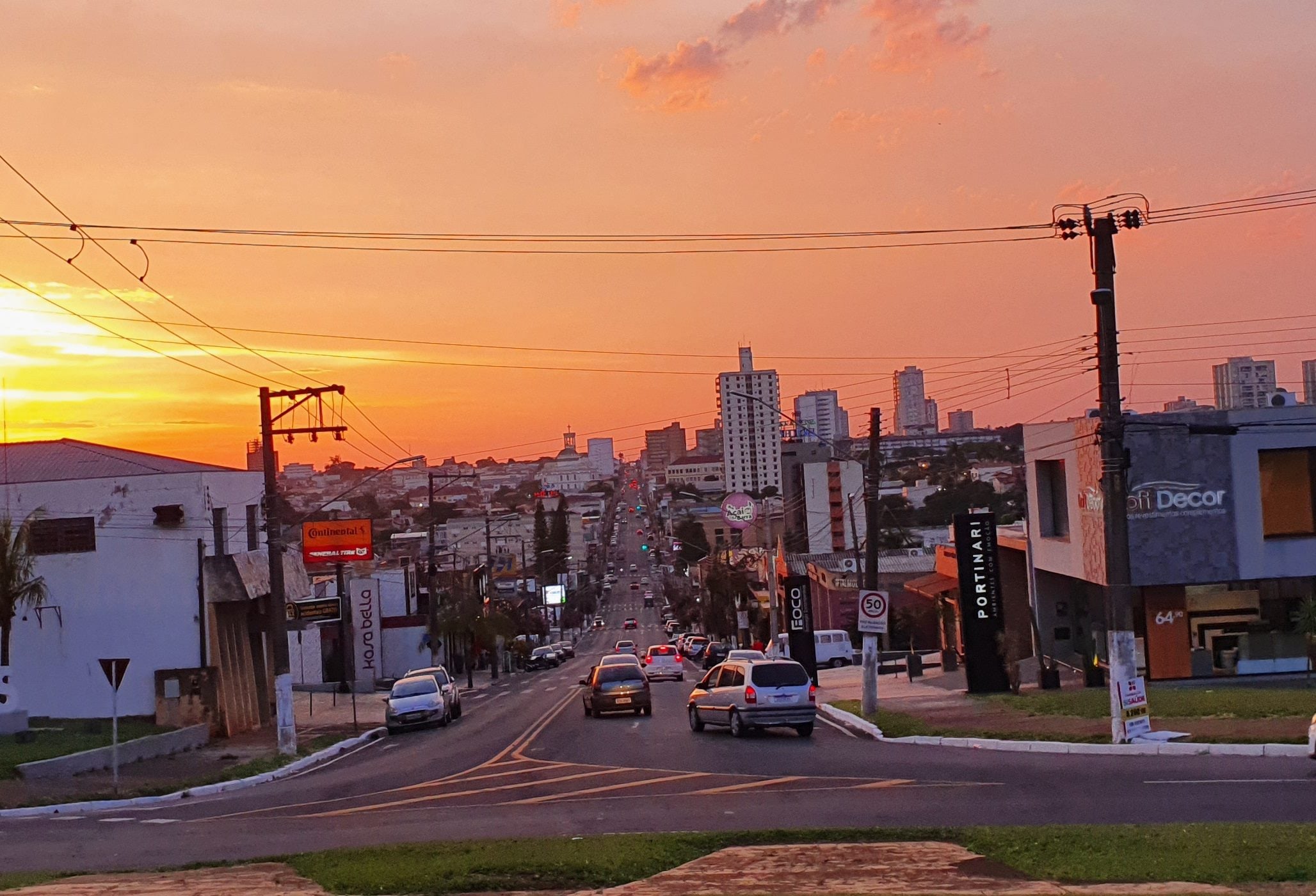 Avenida Rui Barbosa ao pôr do sol, com os prédios do centro de Assis ao fundo