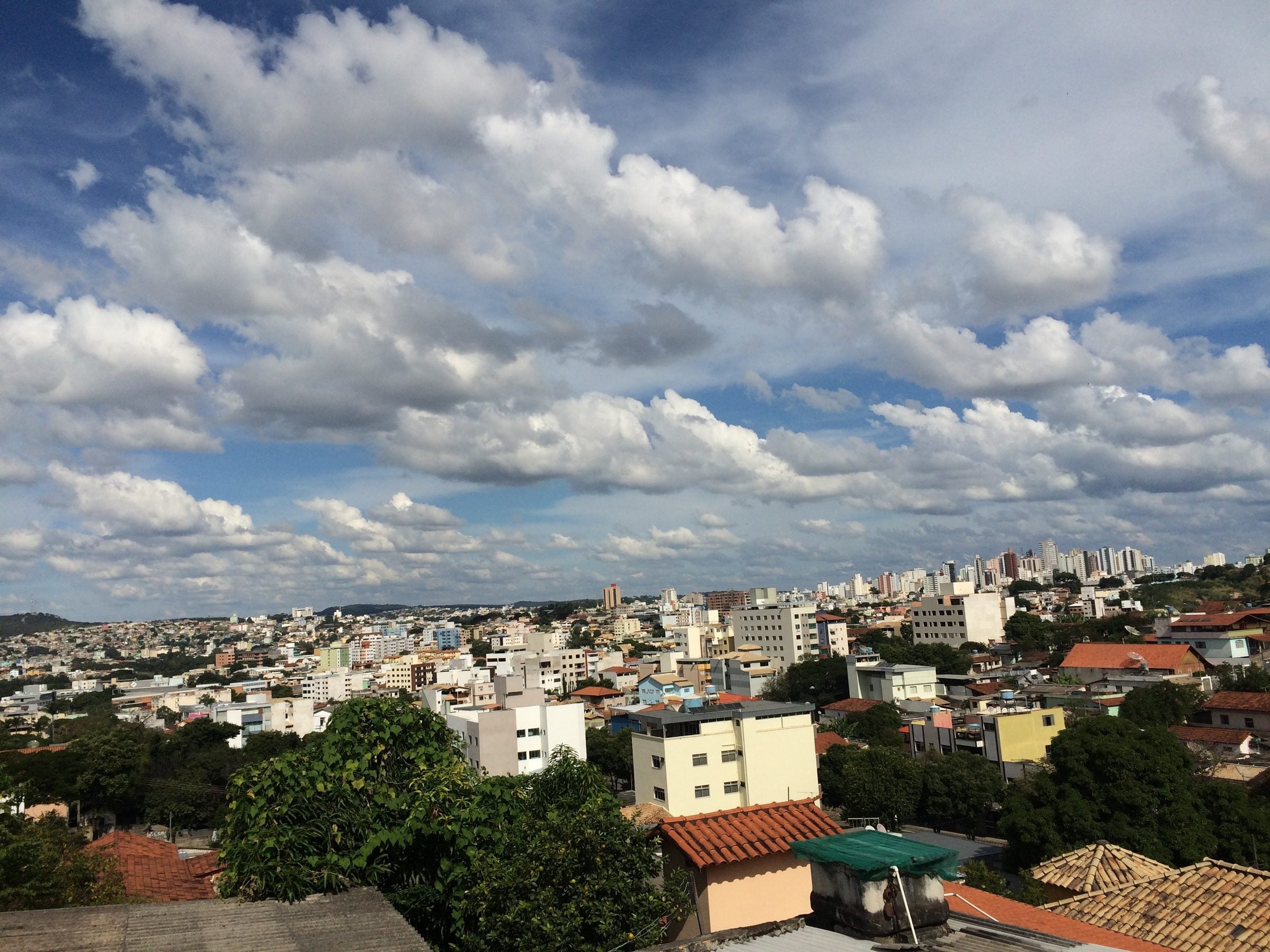 Vista geral de Divinópolis, com os prédios do centro sob um céu de nuvens