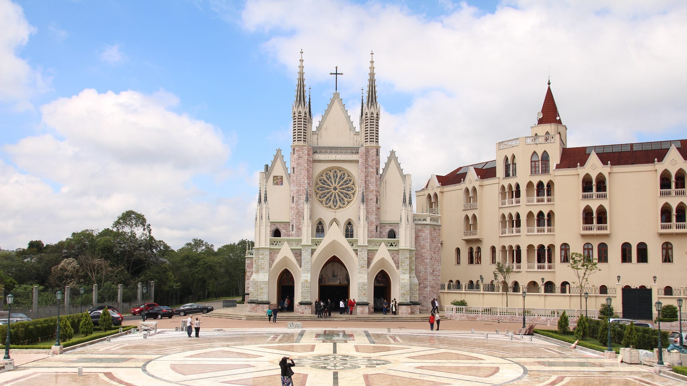 Basílica de Nossa Senhora do Rosário de Fátima e sua grande praça em Embu das Artes, sob céu azul com nuvens
