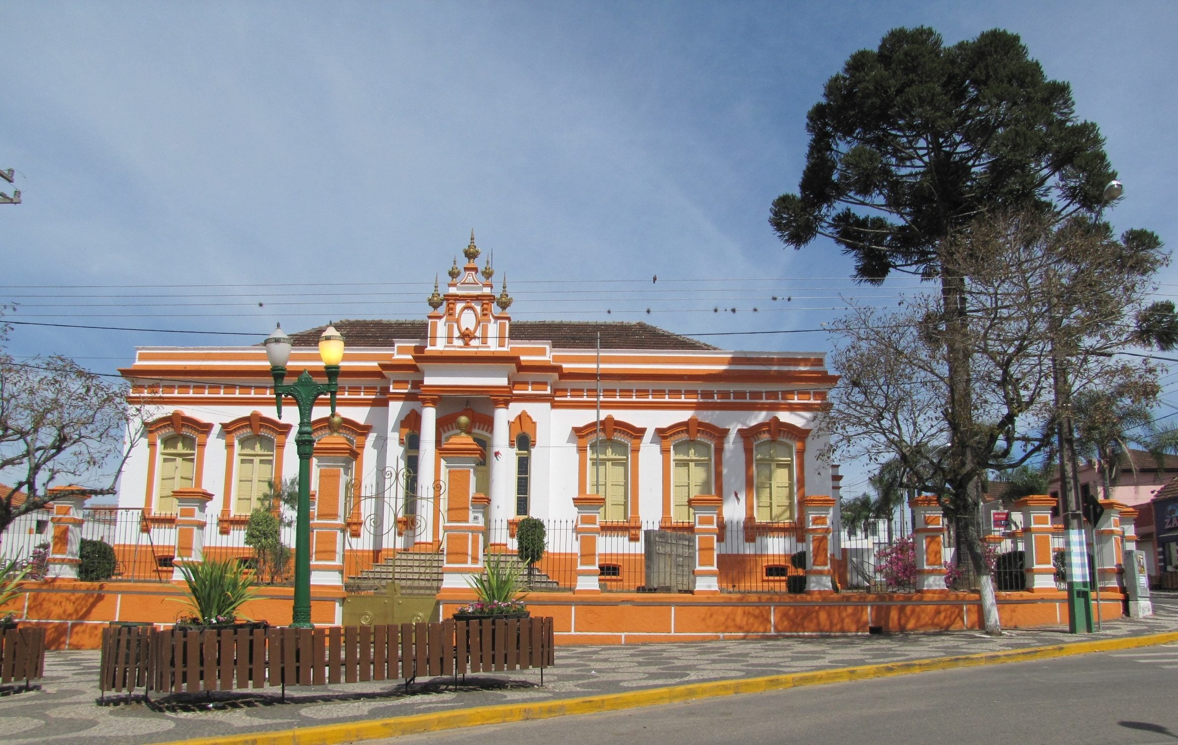 Prédio histórico da antiga Coletoria de Palmeira, com fachada ornamentada, ao lado de uma araucária
