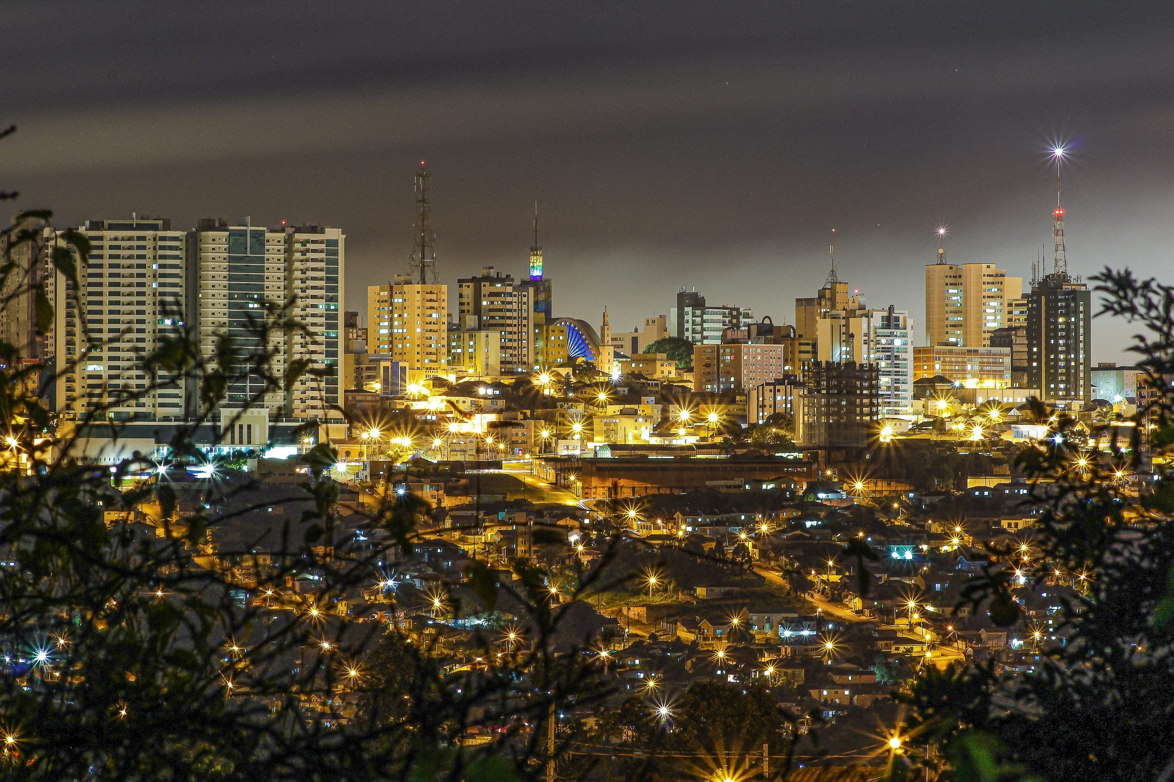 Vista noturna do centro de Ponta Grossa, com os prédios iluminados e a Catedral de Sant'Ana ao centro
