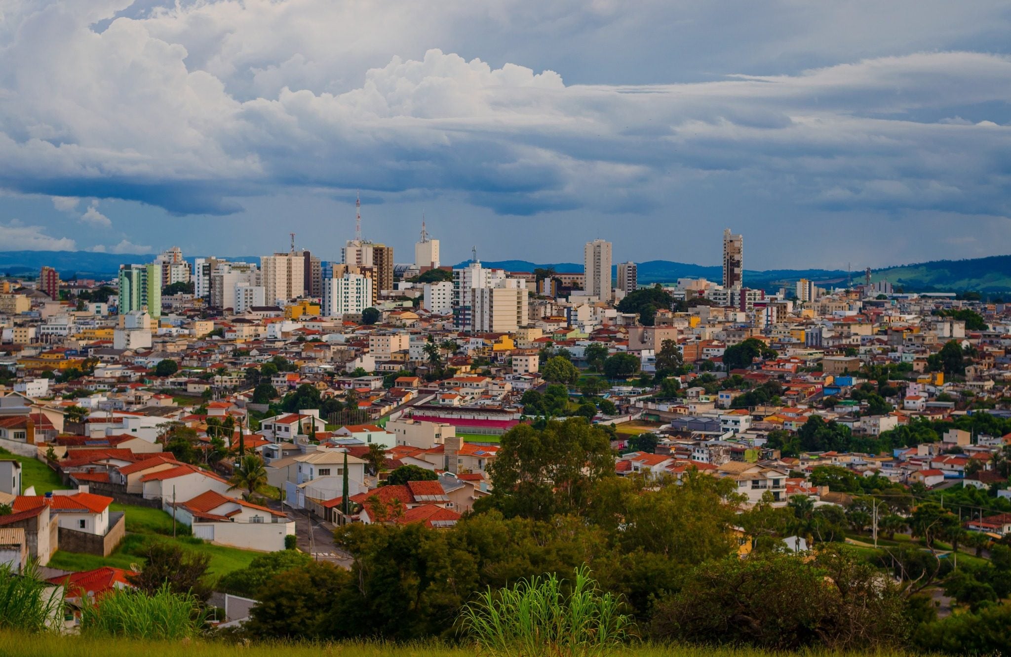 Vista panorâmica de Varginha, com os prédios do centro e os bairros ao redor sob céu com nuvens